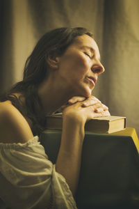 Woman in a white blouse with a carmen neckline with her hands resting on an old book 
