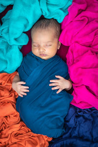 Cute newborn baby sleeping in baby wrap in unique style from top angle shot