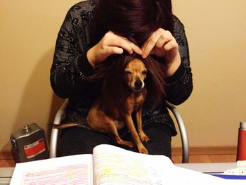 Woman with dog sitting on table at home