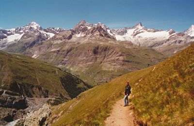 Rear view of man walking on mountain against sky