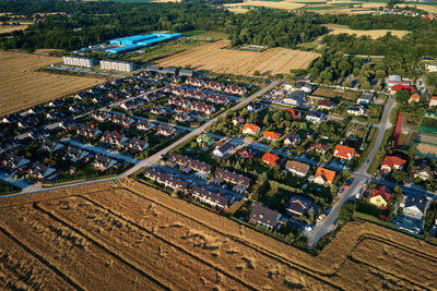 Residential houses in small town near agricultural field, aerial view