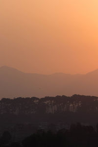 Scenic view of silhouette mountains against orange sky