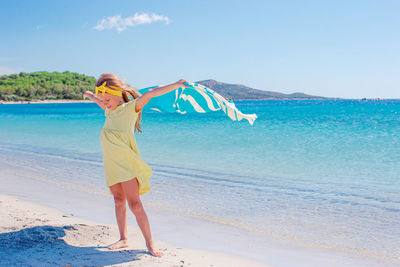 Woman standing at beach against sky
