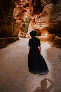 Rear view of woman standing against rock formation