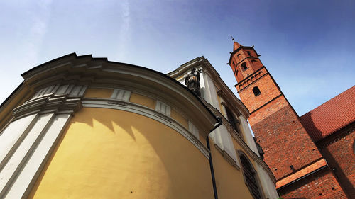 Low angle view of clock tower amidst buildings against sky