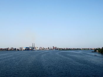 View of city at waterfront against blue sky