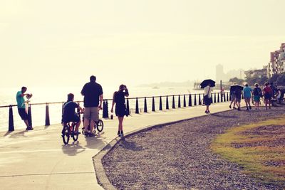 People on road by sea against sky