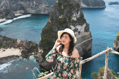 Young woman standing on rock by sea