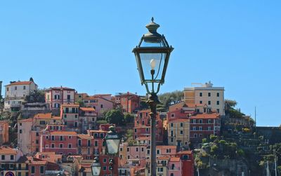 Street light amidst buildings against clear blue sky