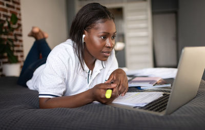 Ethnic student making video call on bed