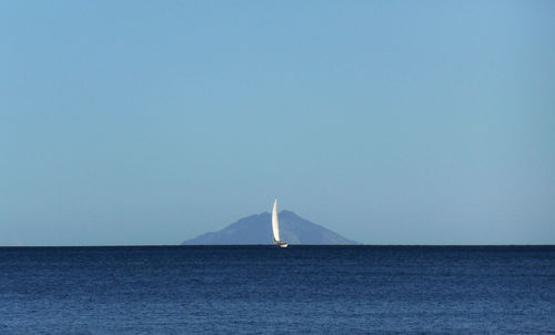 Sailboat in sea against clear blue sky