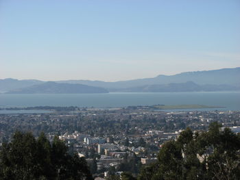 High angle view of cityscape by sea against clear sky