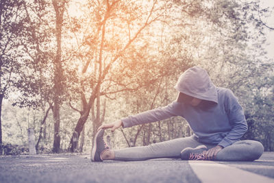 Woman exercising on road amidst trees