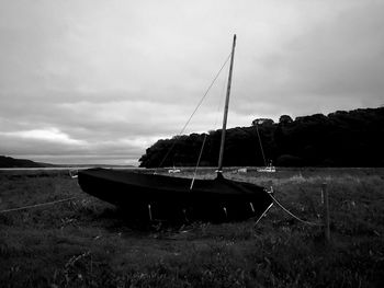 Sailboats moored on field against sky