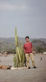 Portrait of smiling man standing by plant against sky