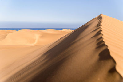 Sand dunes in desert against clear sky