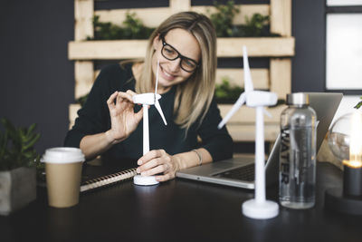 Young woman using mobile phone while sitting on table