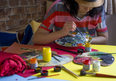 Midsection of woman holding multi colored umbrellas on table