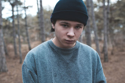 Sad teenage boy 17-18 year old wearing knitted hat and sweatshirt outdoors. teen problem concept