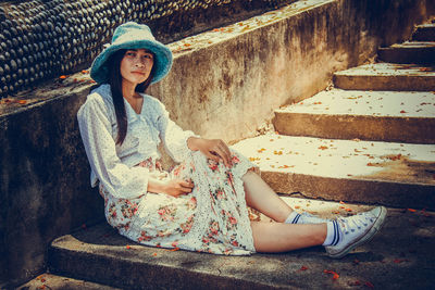 Young woman wearing hat sitting outdoors