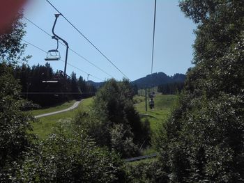 Overhead cable car on field against sky