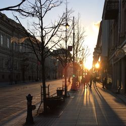 People on sidewalk in city at sunset