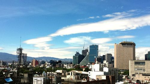 Buildings in city against cloudy sky