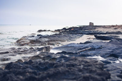 Rocks on beach against clear sky