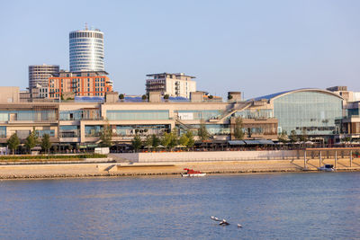 Buildings by sea against clear sky