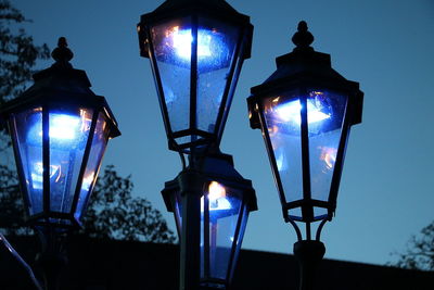 Low angle view of illuminated street light against blue sky