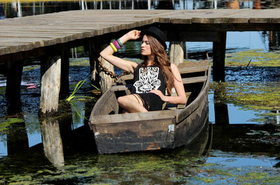 Woman sitting on wooden boat in lake
