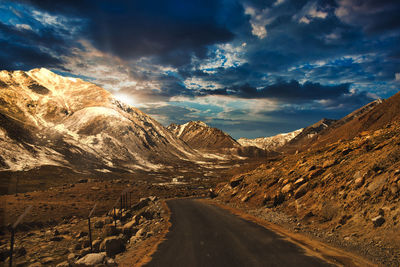 Road amidst snowcapped mountains against sky