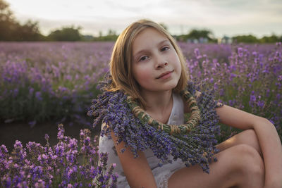 Portrait of beautiful woman with purple flowers on field