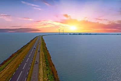 Scenic view of road in sea against sky during sunset