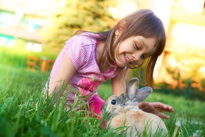 Portrait of cute girl with rabbit on grass