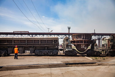 Rear view of man standing on railroad track against sky