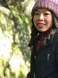 Portrait of smiling young woman wearing warm clothes while standing outdoors