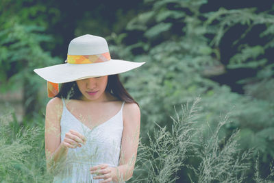 Woman wearing hat while standing by plants