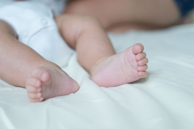 Low section of baby lying on bed
