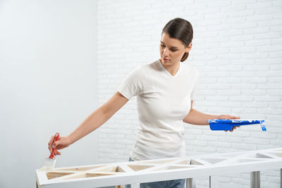 Young woman looking away while standing against wall