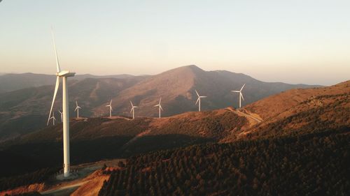 Wind turbines on land against clear sky