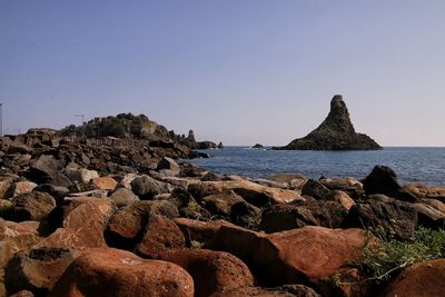 Scenic view of rocks on beach against clear sky