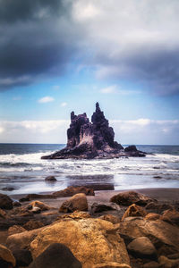 Scenic view of rocks on beach against sky