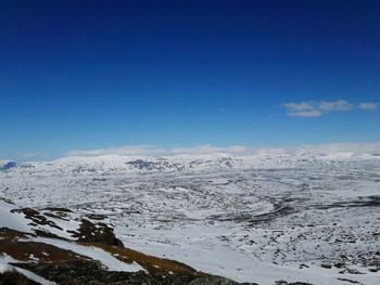 Scenic view of snowcapped landscape against blue sky