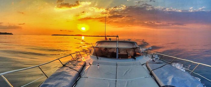 Boat sailing on sea against sky during sunset