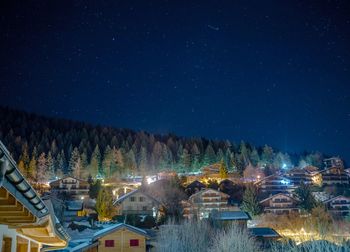 Illuminated houses against sky at night