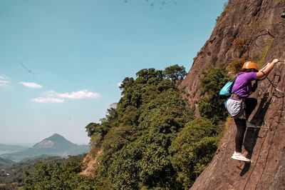 Rear view of man standing on mountain against clear sky