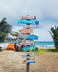 Information sign on beach against sky