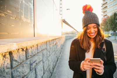 Smiling young woman using mobile phone in winter