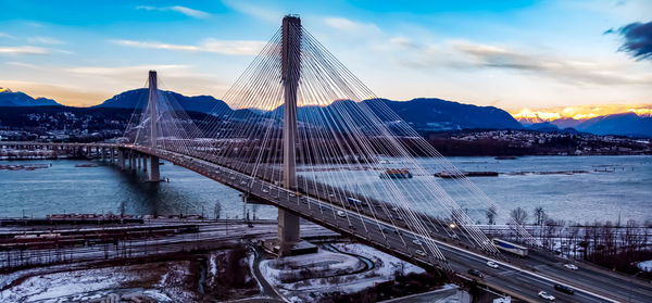 Bridge over river against sky at sunset